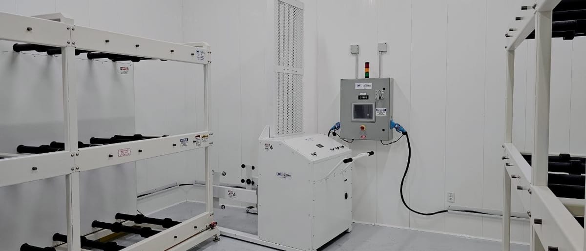 Barrel handler standing in a finished white process room beside its floor-mounted control cabinet, with barrel racks racked to both sides.